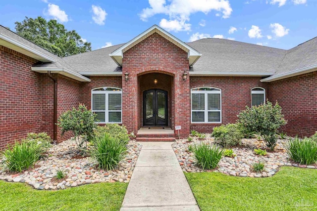 2882 Tunnel Rd, Pace, FL 32571 - view of exterior entry with roof with shingles, brick siding, french doors, and a yard