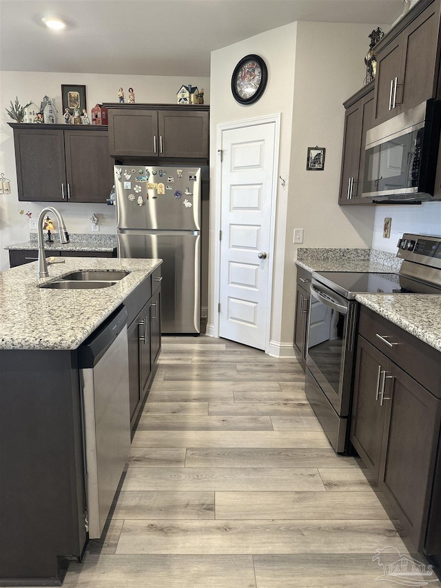 2656 Avalon St, Cantonment, FL 32533 - kitchen with dark brown cabinetry, light wood-type flooring, light stone counters, a sink, and stainless steel appliances