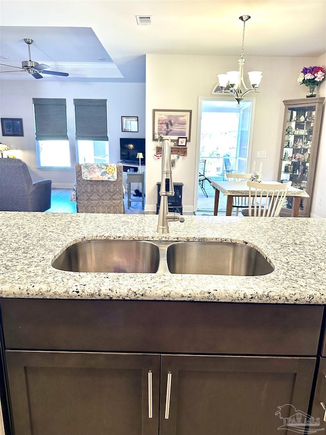 2656 Avalon St, Cantonment, FL 32533 - kitchen featuring visible vents, dark brown cabinetry, light stone countertops, a sink, and ceiling fan with notable chandelier