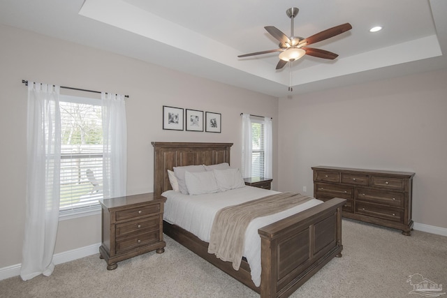 bedroom with ceiling fan, recessed lighting, light colored carpet, baseboards, and a raised ceiling