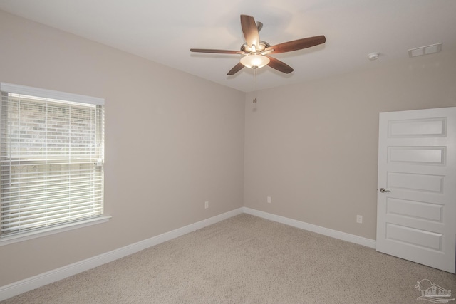 empty room featuring a ceiling fan, light carpet, visible vents, and baseboards