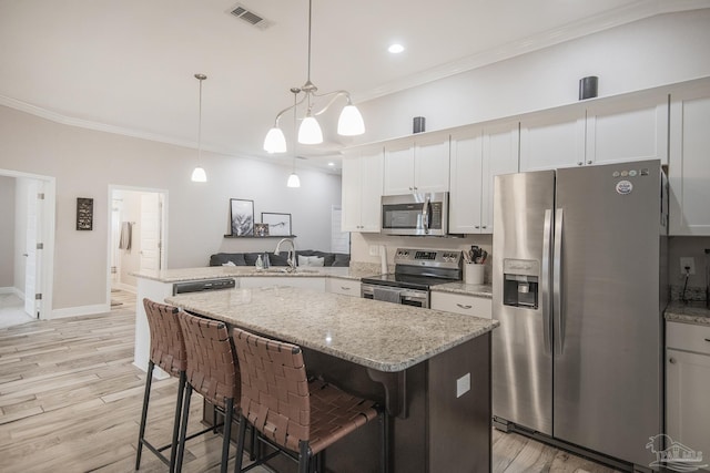 kitchen with visible vents, appliances with stainless steel finishes, a peninsula, crown molding, and a sink