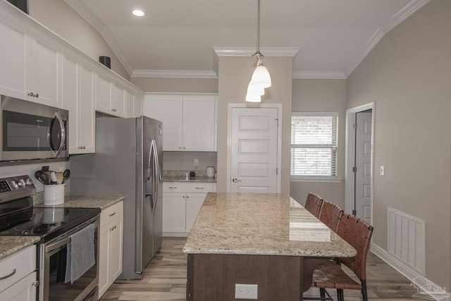 kitchen with a kitchen breakfast bar, stainless steel appliances, visible vents, and crown molding