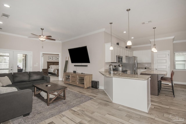 living room featuring light wood-type flooring, visible vents, and crown molding