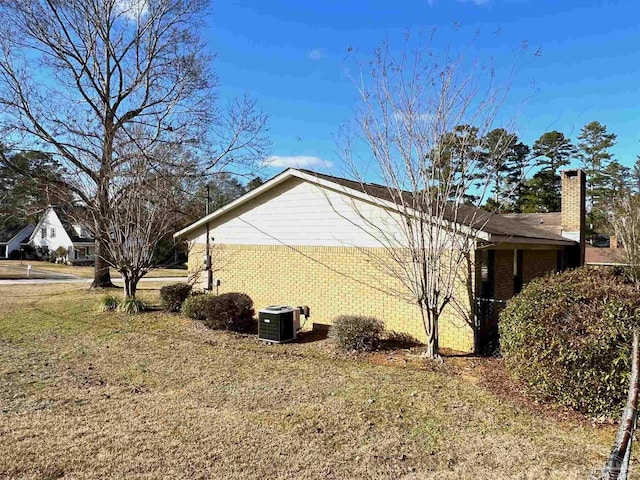 view of side of home with a lawn and central AC unit