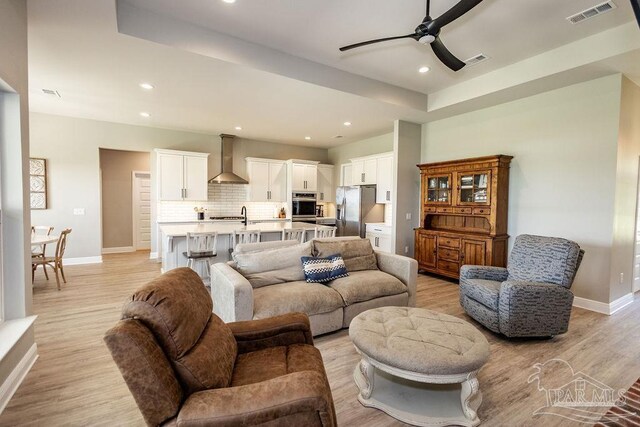 living room with ceiling fan, sink, and light hardwood / wood-style flooring