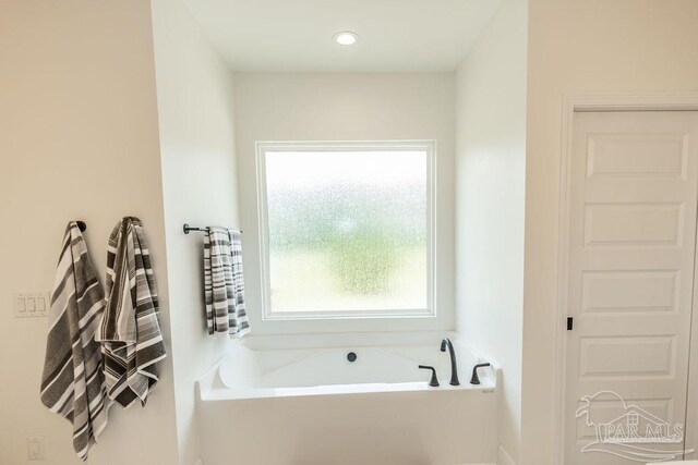 bathroom with a wealth of natural light and a bath