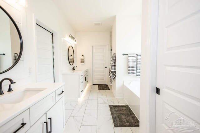 bathroom featuring a tub to relax in, tile patterned floors, and dual bowl vanity