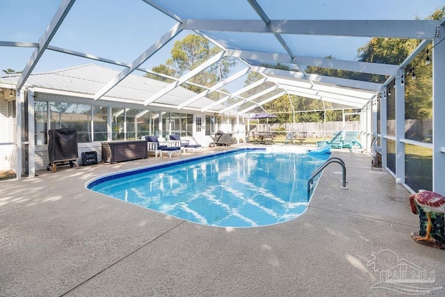 view of swimming pool featuring a lanai and a patio