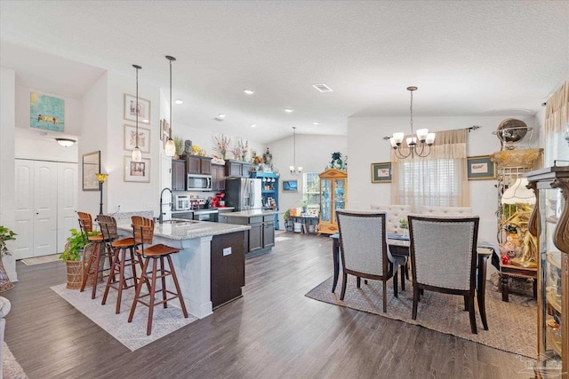 6135 Redberry Dr, Gulf Breeze, FL 32563 - kitchen with stainless steel appliances, a chandelier, dark wood finished floors, a breakfast bar area, and a textured ceiling
