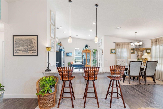 6135 Redberry Dr, Gulf Breeze, FL 32563 - kitchen featuring a chandelier, wood finished floors, vaulted ceiling, light stone countertops, and hanging light fixtures