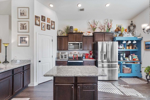 6135 Redberry Dr, Gulf Breeze, FL 32563 - kitchen featuring appliances with stainless steel finishes, dark wood-style floors, dark brown cabinets, light stone countertops, and a center island