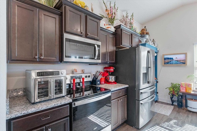 6135 Redberry Dr, Gulf Breeze, FL 32563 - kitchen featuring stainless steel appliances, dark brown cabinets, wood finished floors, vaulted ceiling, and light stone counters