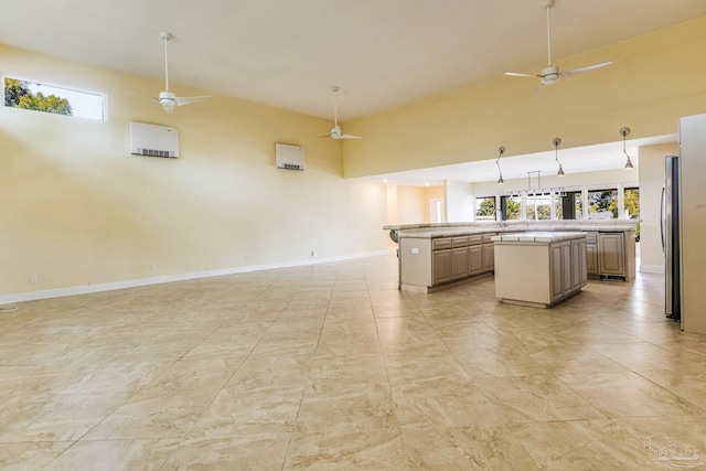 kitchen featuring stainless steel fridge, ceiling fan, a center island, and a towering ceiling