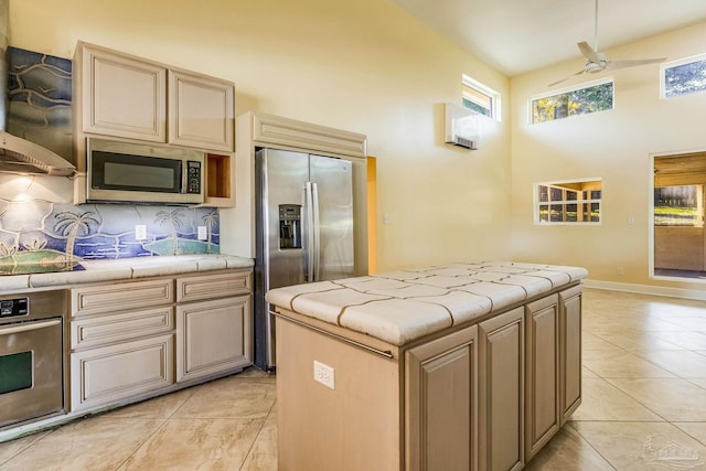 kitchen featuring ceiling fan, a center island, light brown cabinets, stainless steel appliances, and backsplash