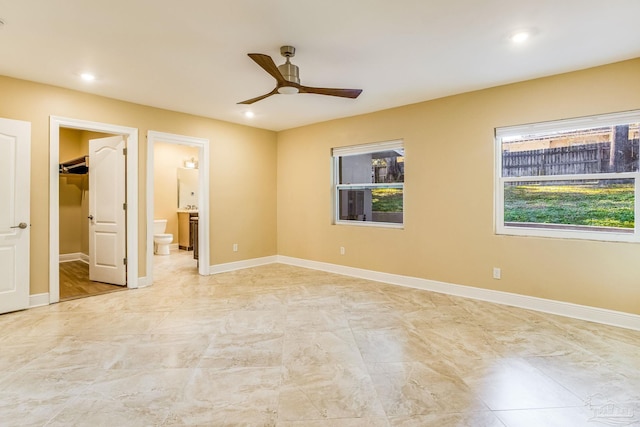 unfurnished bedroom with ensuite bathroom, ceiling fan, a spacious closet, and a closet