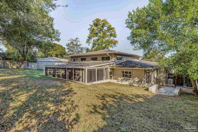 back of house featuring a yard, a patio, and a sunroom