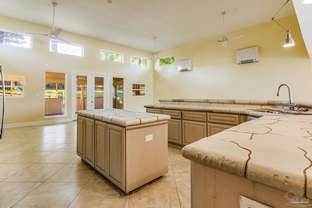 kitchen featuring light brown cabinetry, french doors, ceiling fan, sink, and a center island