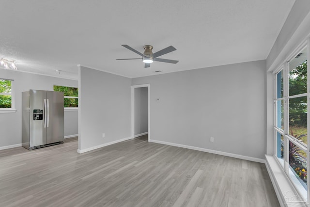 empty room featuring light wood-type flooring, a textured ceiling, ceiling fan, and a healthy amount of sunlight