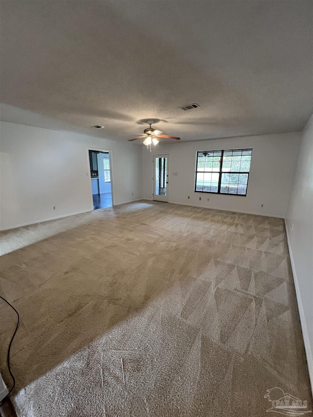 spare room with light carpet, ceiling fan, a textured ceiling, and visible vents