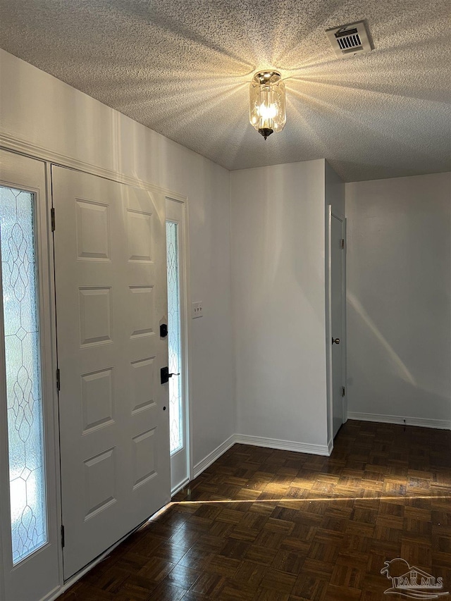 entrance foyer featuring visible vents, a textured ceiling, and baseboards