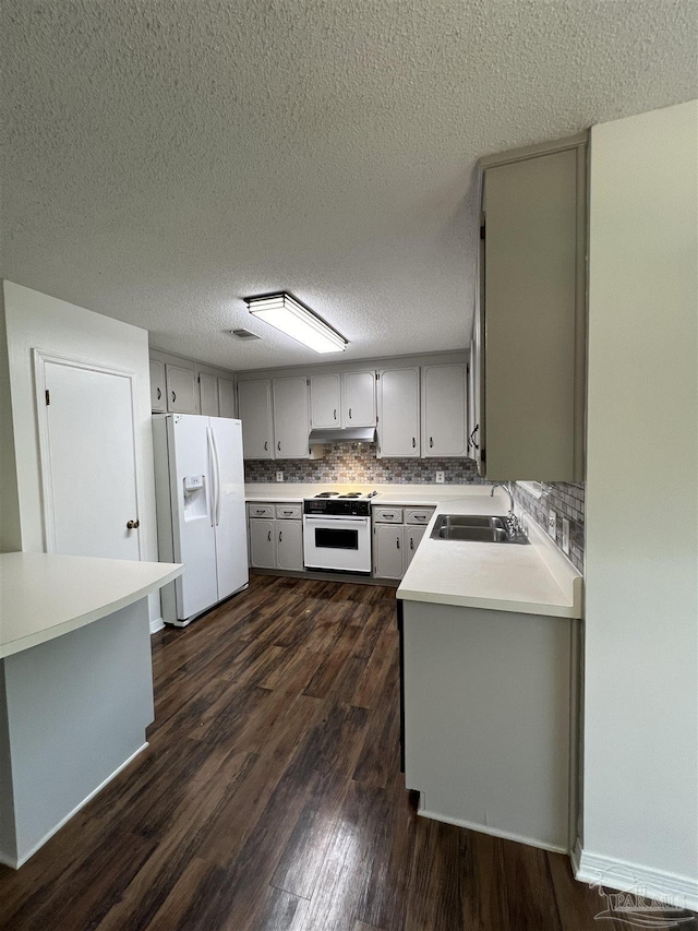 kitchen with white appliances, tasteful backsplash, light countertops, under cabinet range hood, and a sink