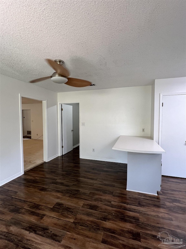 spare room with dark wood-style floors, ceiling fan, a textured ceiling, and baseboards