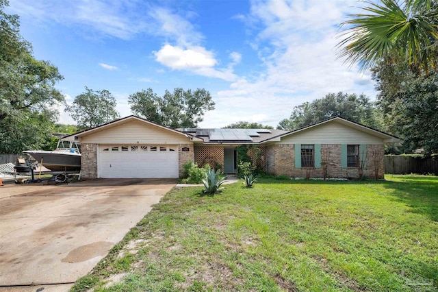 single story home with a garage, driveway, a front yard, roof mounted solar panels, and brick siding