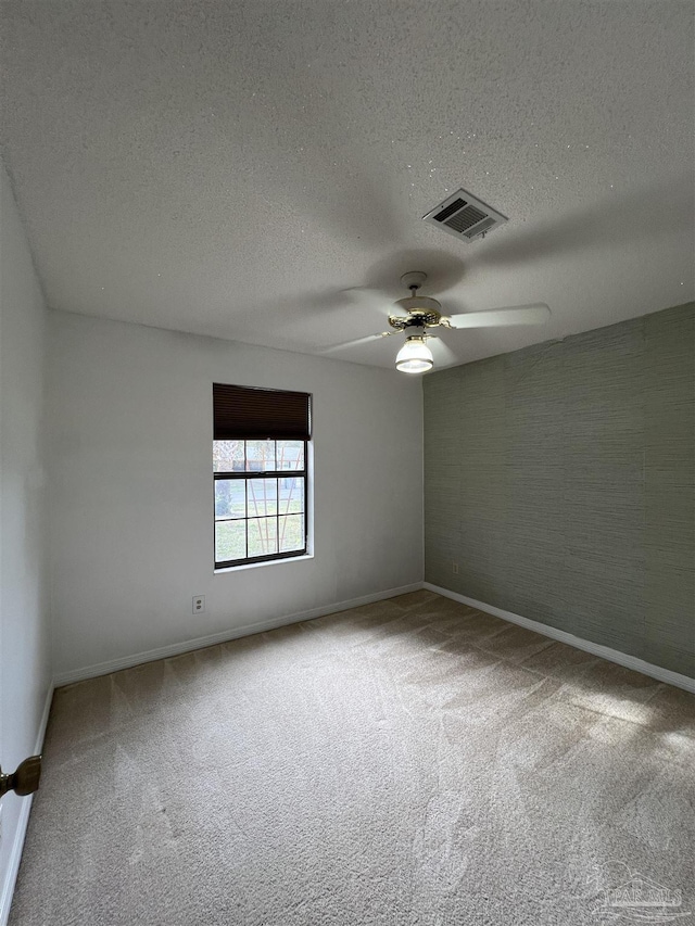 empty room featuring carpet, visible vents, and a textured ceiling