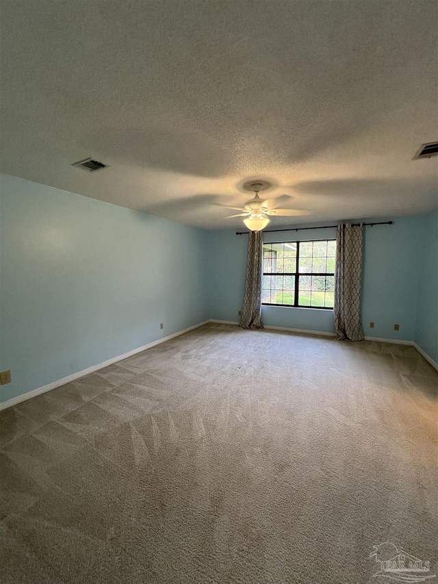 spare room featuring ceiling fan, carpet, and visible vents