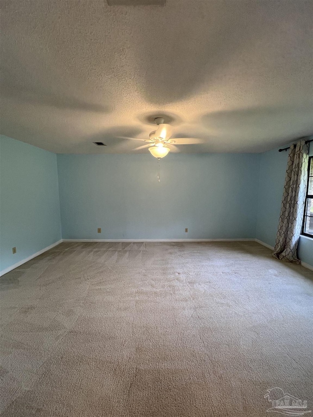 carpeted empty room featuring a ceiling fan, visible vents, and a textured ceiling