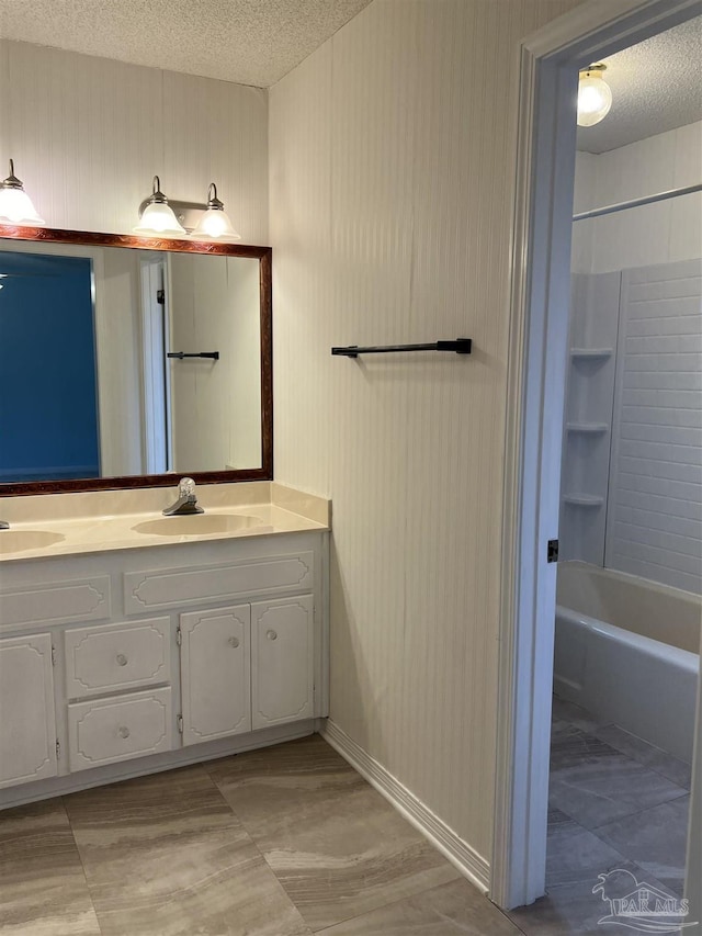 bathroom featuring a textured ceiling, double vanity, shower / bathing tub combination, and a sink