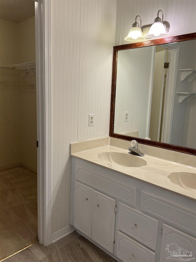 full bath with a walk in closet, a sink, and double vanity