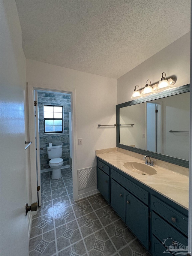 bathroom with a textured ceiling, toilet, tile patterned flooring, and vanity