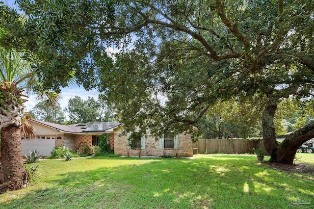 view of front facade with a garage, a front lawn, fence, and brick siding