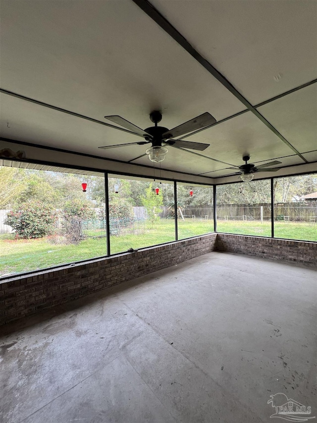 unfurnished sunroom featuring a ceiling fan and plenty of natural light