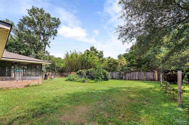 view of yard with a sunroom and a fenced backyard