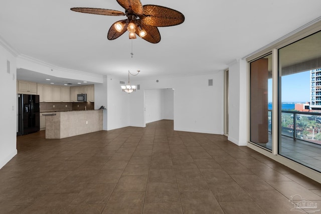 unfurnished living room featuring ceiling fan with notable chandelier, ornamental molding, and dark tile patterned flooring