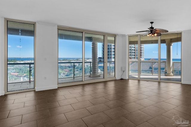 empty room featuring floor to ceiling windows, ceiling fan, and a water view