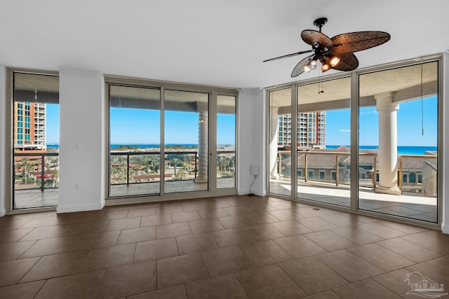 spare room with ceiling fan, a wall of windows, and a water view