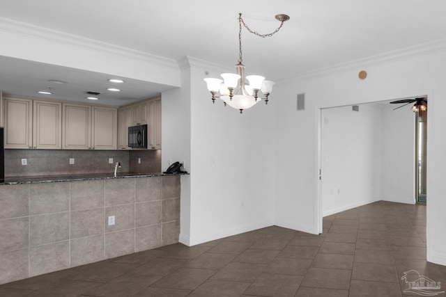 kitchen featuring cream cabinetry, ornamental molding, dark tile patterned flooring, tasteful backsplash, and ceiling fan with notable chandelier