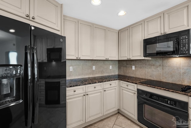 kitchen featuring light tile patterned floors, black appliances, decorative backsplash, and dark stone counters