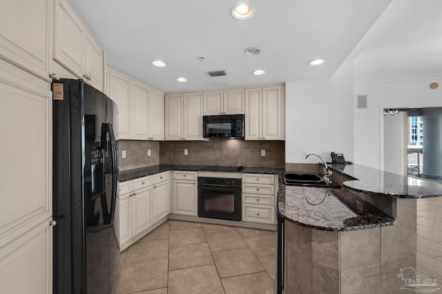 kitchen featuring black appliances, kitchen peninsula, light tile patterned floors, dark stone counters, and sink