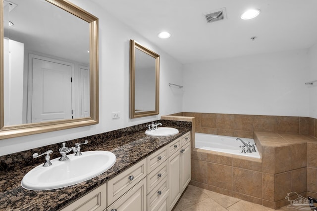 bathroom featuring tiled bath, tile patterned flooring, and vanity