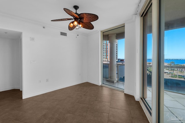 spare room featuring a water view, dark tile patterned flooring, ceiling fan, ornamental molding, and floor to ceiling windows