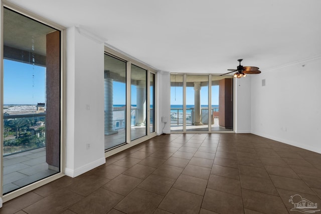 tiled spare room with ceiling fan, a wall of windows, and a water view