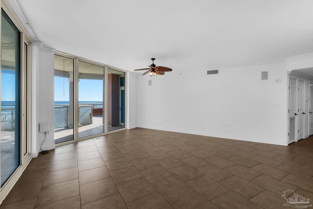 tiled spare room featuring ceiling fan, a wall of windows, and a water view