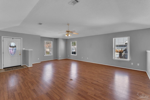 unfurnished living room with dark hardwood / wood-style flooring, ceiling fan, and a textured ceiling