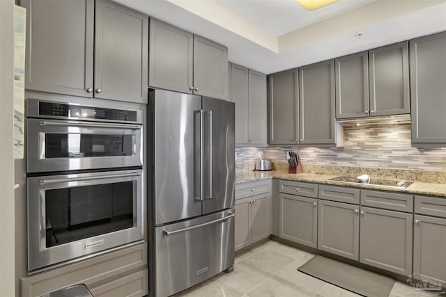 kitchen featuring light stone counters, gray cabinets, and stainless steel appliances