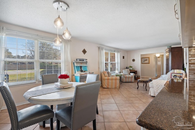 dining room with light tile patterned floors, a textured ceiling, and baseboards